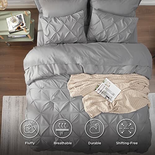 Gray comforter set with pillows and blanket on bed.