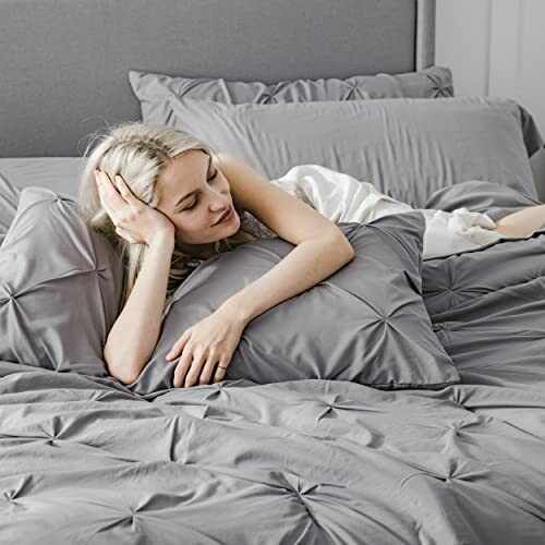 Woman relaxing on a bed with gray bedding.